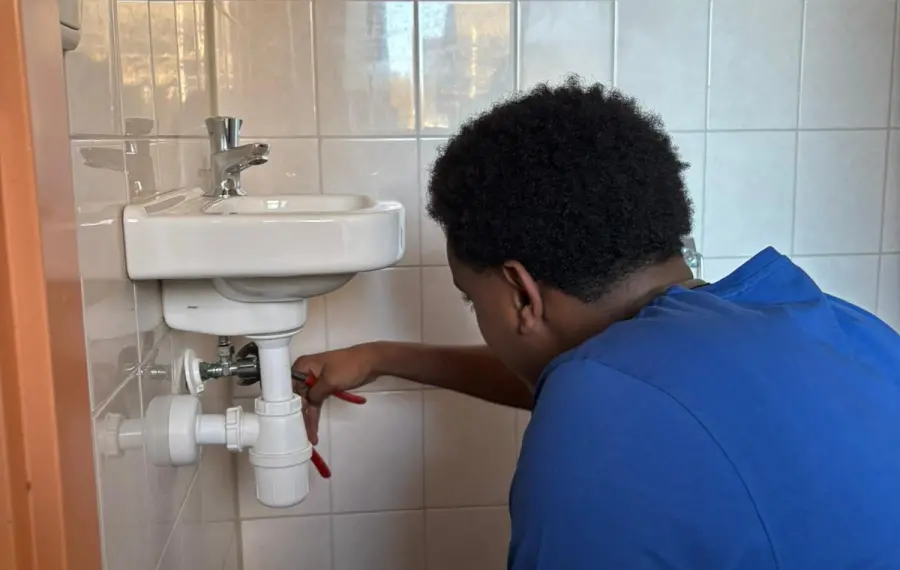 Monteur sluit een wastafel aan in een badkamer