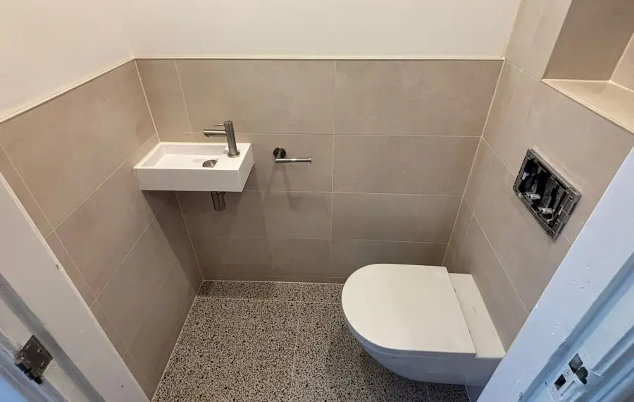 Afgewerkte badkamer met hangend toilet en fontein