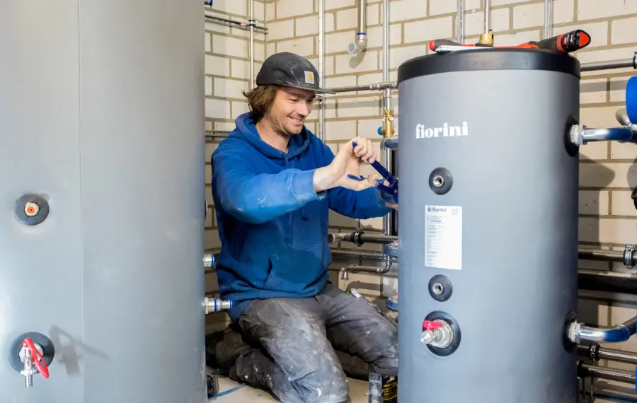 Monteur monteert leidingen aan een boilervat